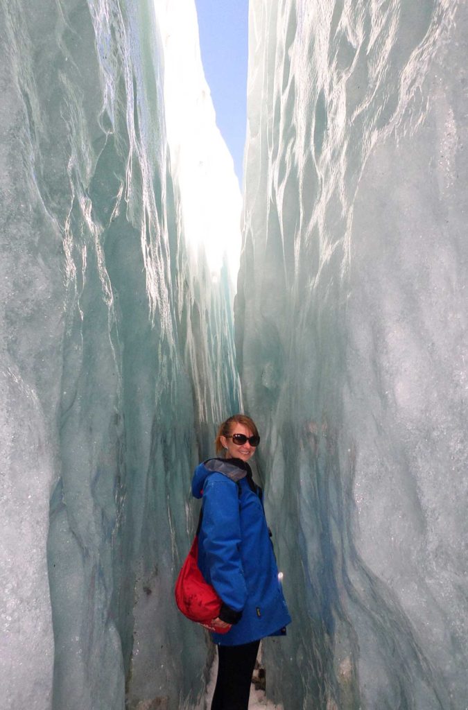 Turista caminha entre paredes de gelo da Geleira Franz Josef