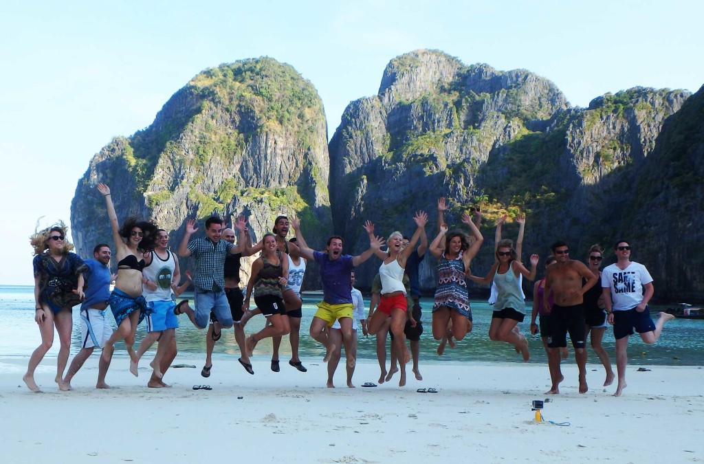 Grupo de turistas salta para foto na praia de Maya Bay, na Tailândia