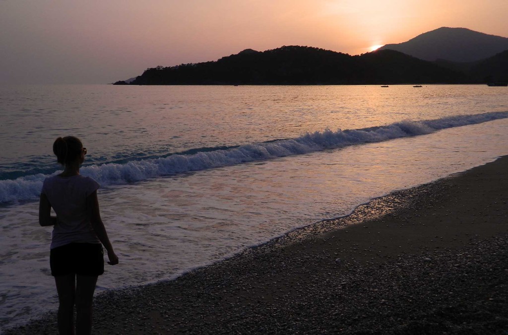 Mulher admira o pôr do sol na praia de Oludeniz, na Turquia