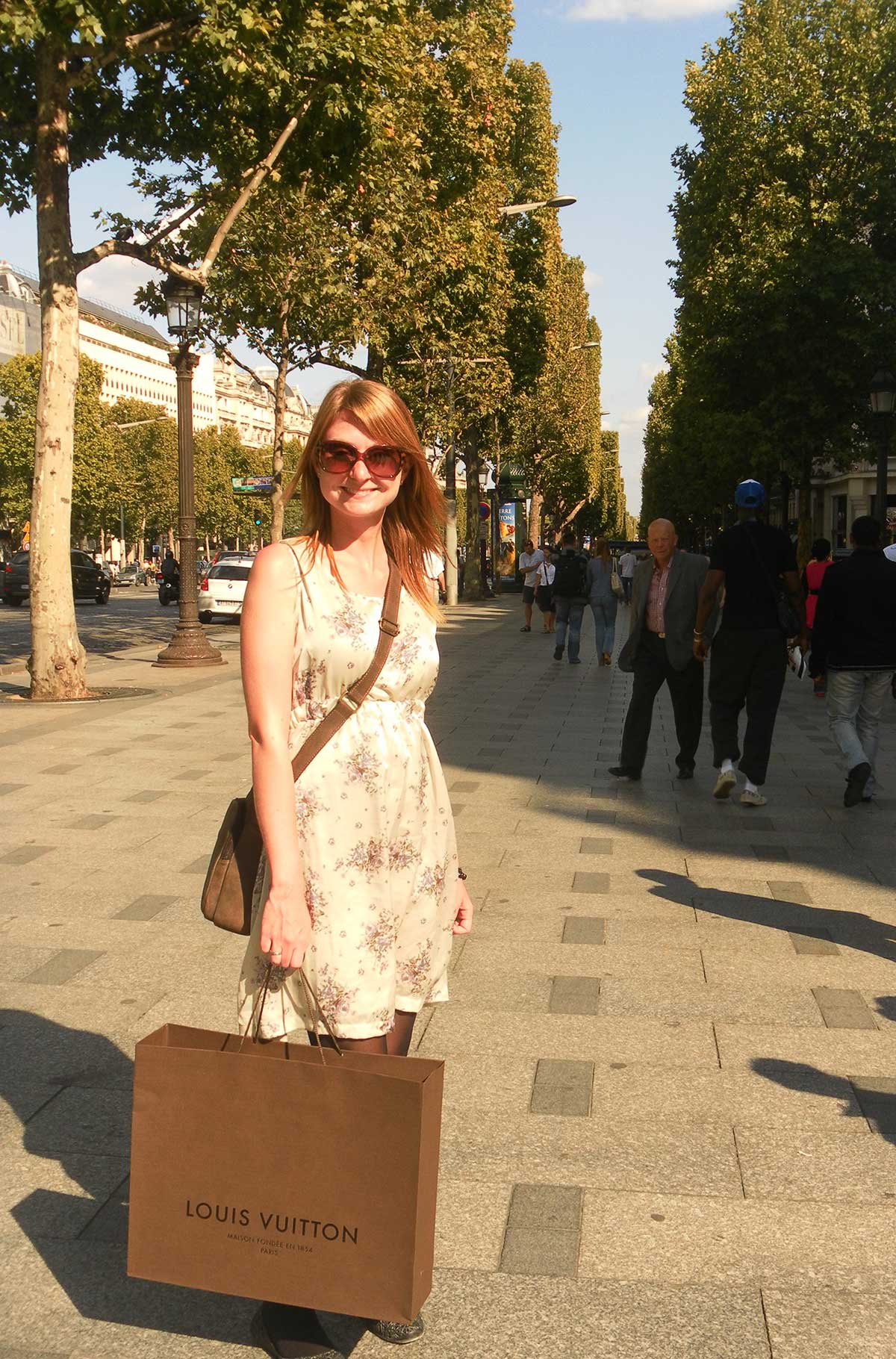 Mulher posa para foto com sacola de compras na Avenida Champs-Élysées, em Paris (França)