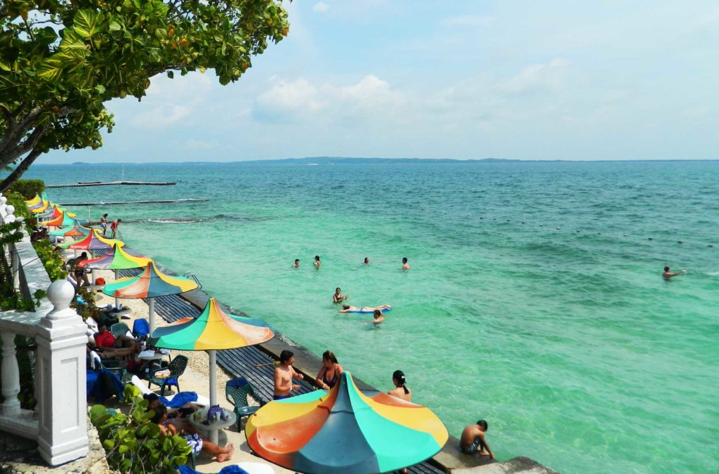 Palapas colorem a praia da Ilha de Cocoliso, em Cartagena, na Colômbia