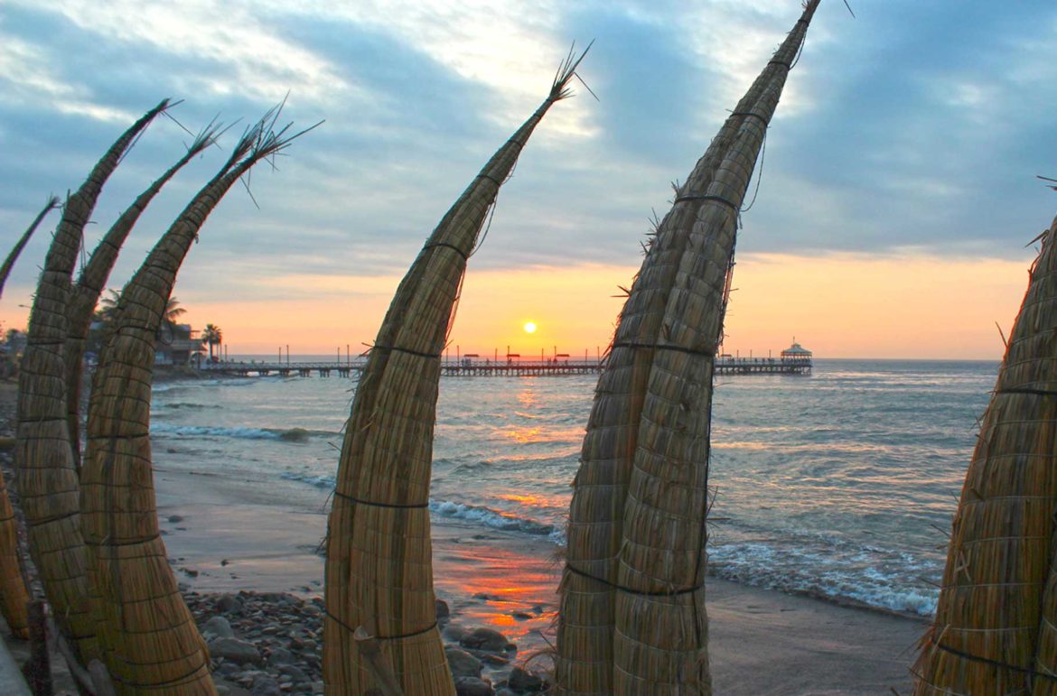 Pôr do sol visto através das tradicionais canoas de totora na Praia de Huanchaco, em Trujiilo (Peru)