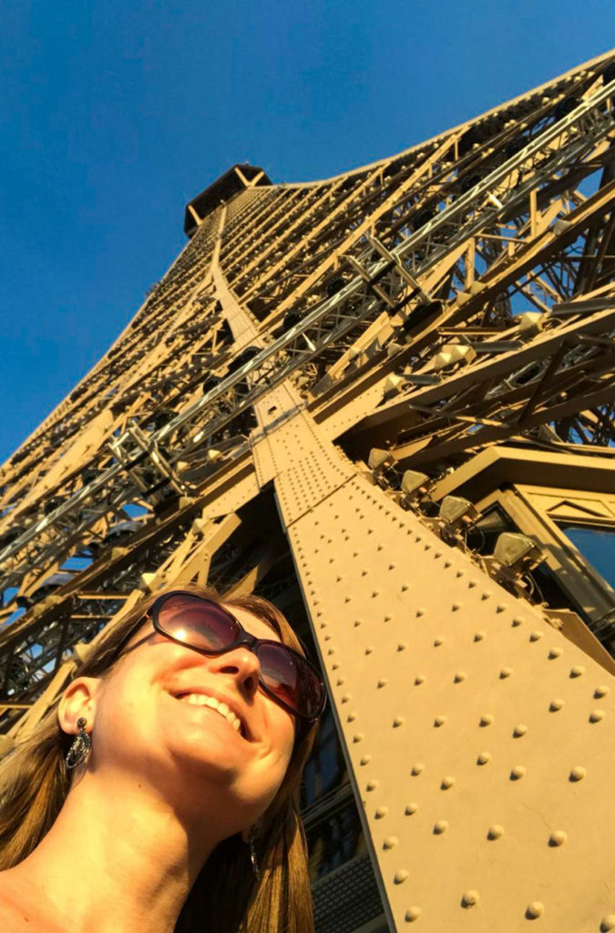 Mulher posa para foto no alto da Torre Eiffel, em Paris (França)