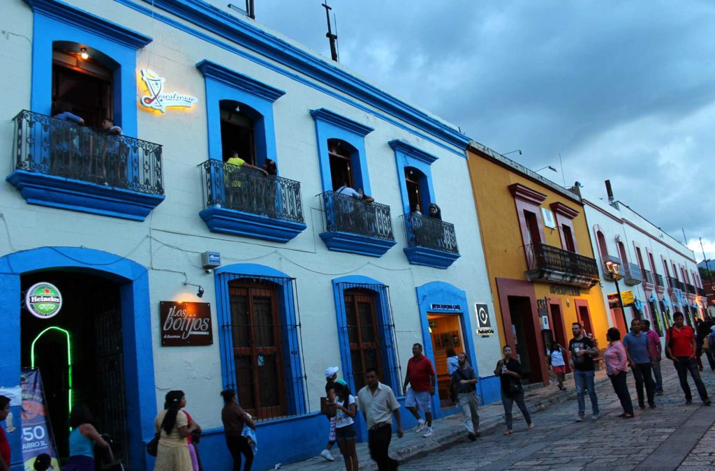 Pessoas caminham pela rua Macedonio Alcalá, no centro histórico de Oaxaca, ao anoitecer