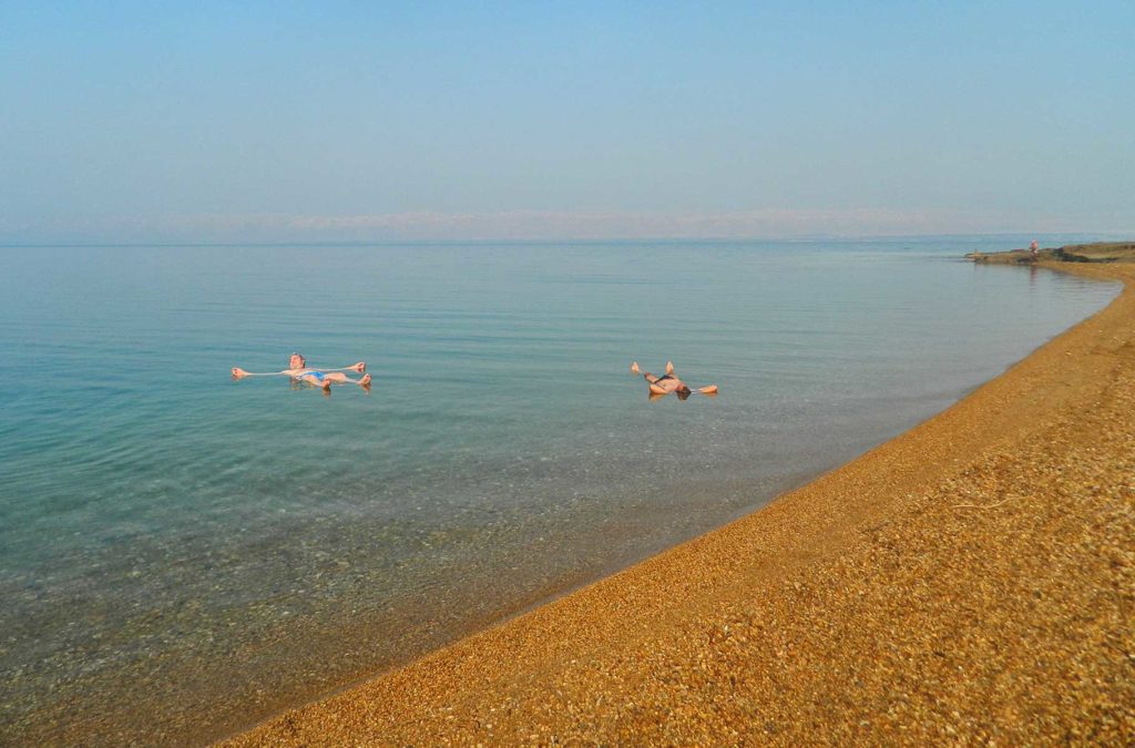 Homens boiam no Mar Morto em praia da Jordânia