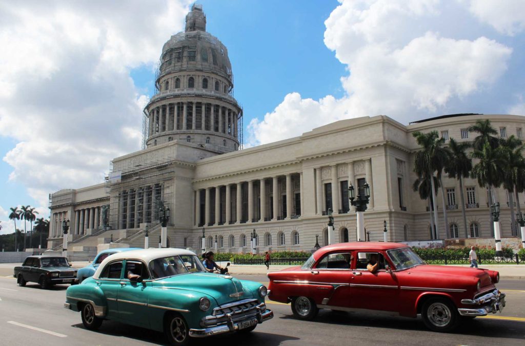 Carros antigos passam em frente ao Capitólio de Havana (Cuba)