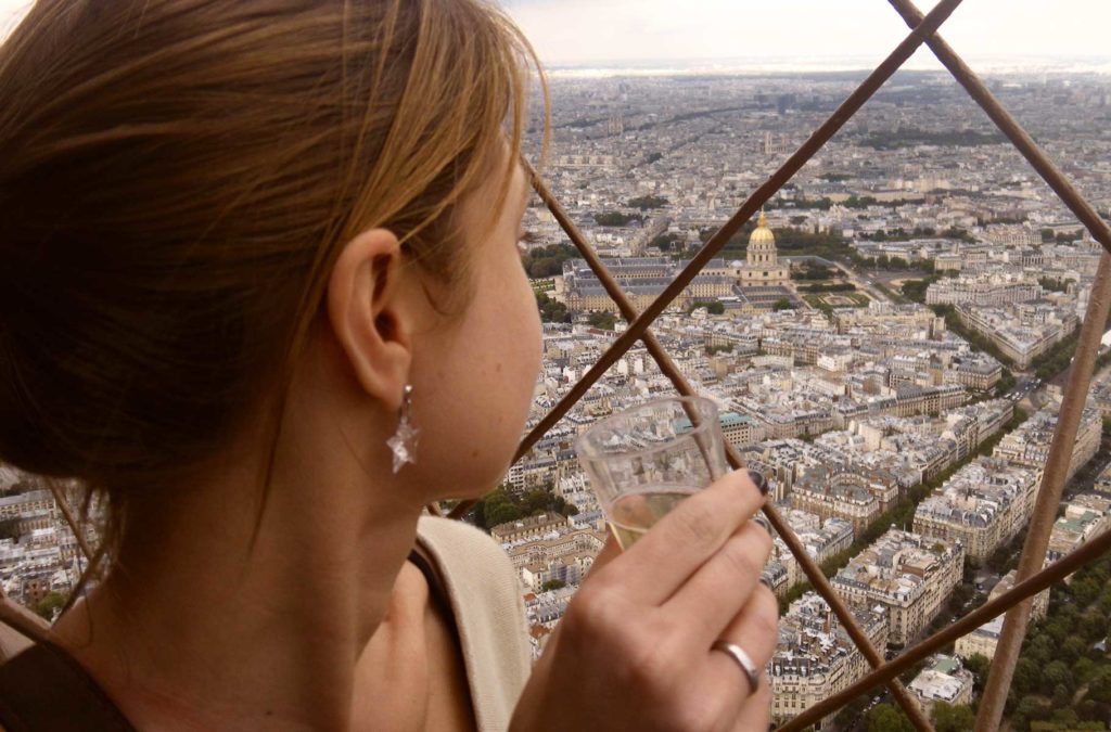 Mulher bebe champanhe no topo da Torre Eiffel, em Paris (França)