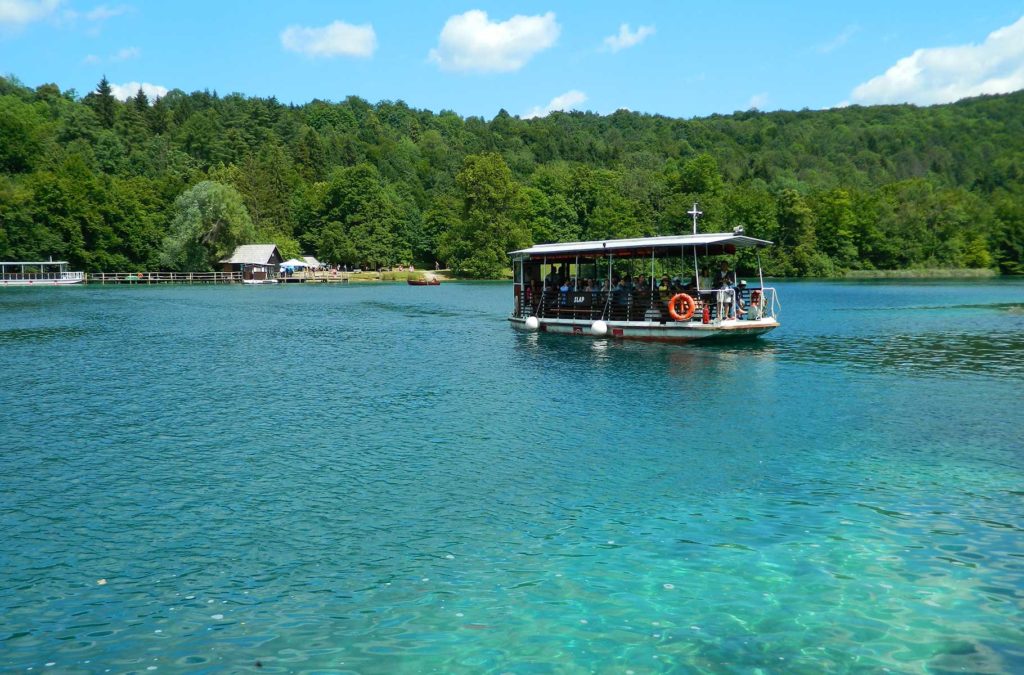 Barco elétrico leva visitante do parque de um lado para o outro do Lago Kozjak