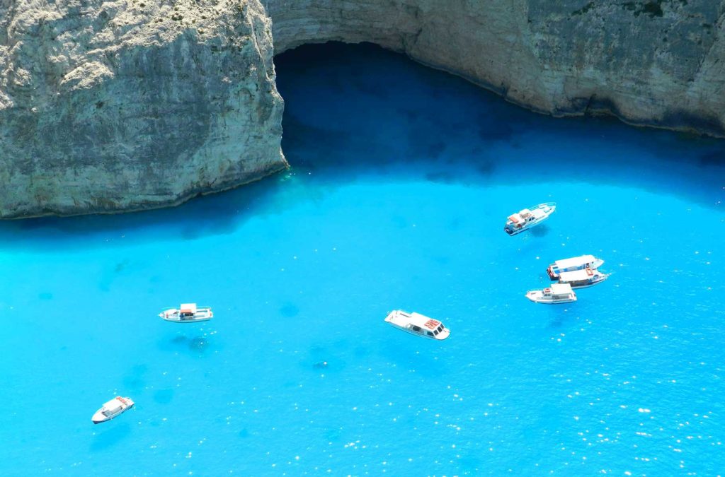 Barcos flutuam no mar próximos aos rochedos da praia de Navagio