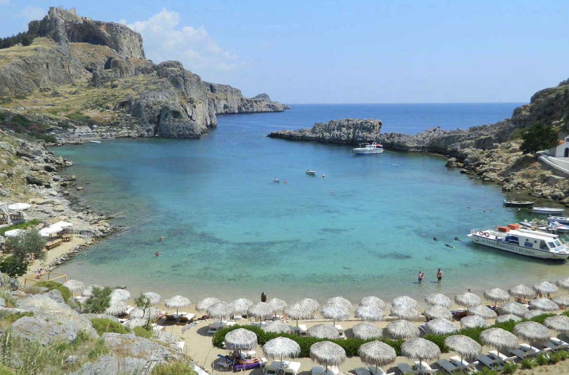 Guarda-sóis cobrem a areia da praia de Saint Paul’s Bay, na Ilha de Rhodes (Grécia)