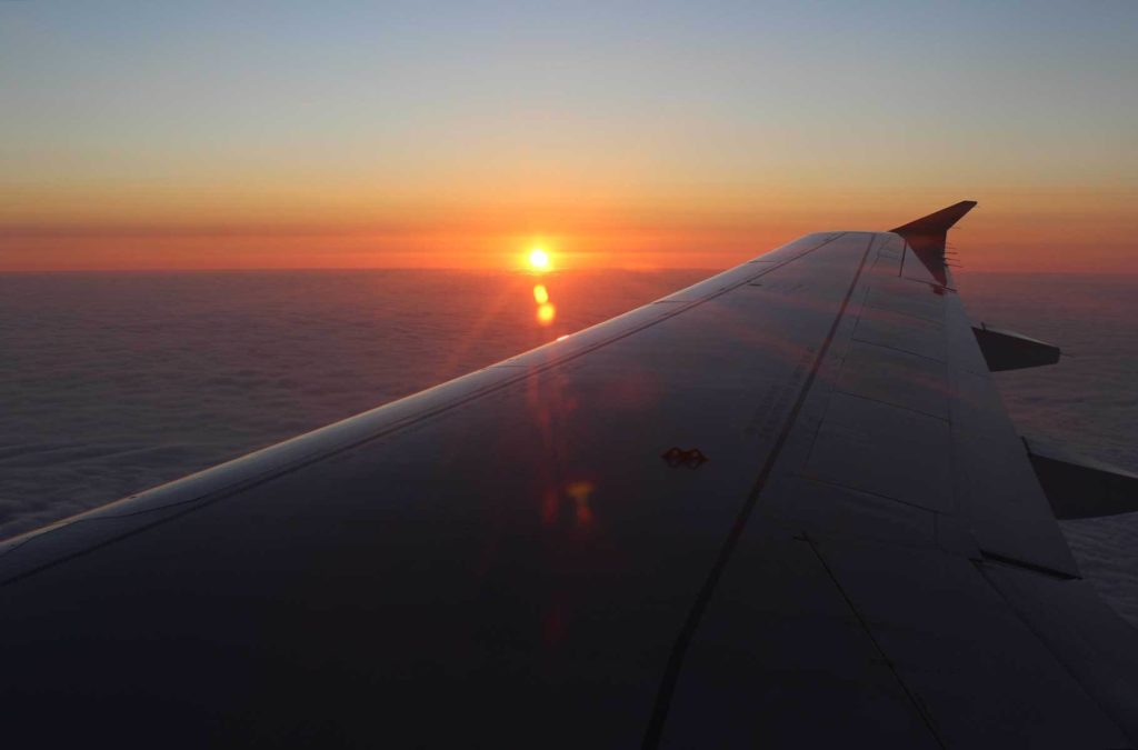 Pôr do sol visto sobre a asa de um avião em pleno voo