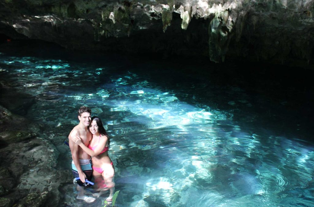 Casal posa para foto abraçado no cenote Dos Ojos, em Tulum (México)