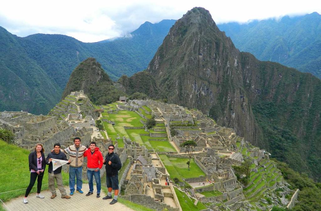 Grupo de turistas posa para foto no sítio arqueológico de Machu Picchu