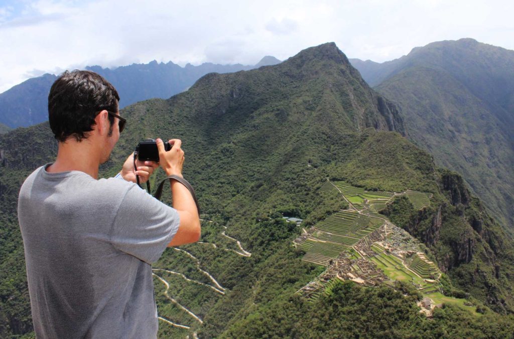 Turista fotografa Machu Picchu vista do alto da Montanha Huayna Picchu