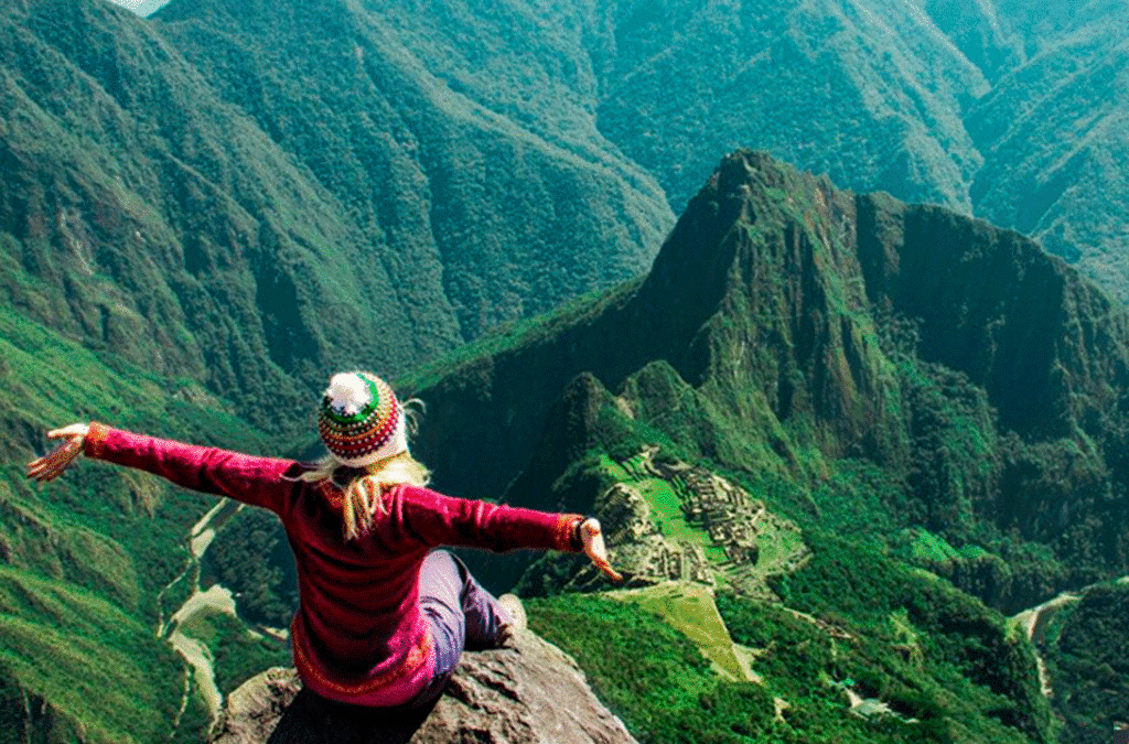 Turista senta na ponta de uma pedra no alto da Montanha Machu Picchu