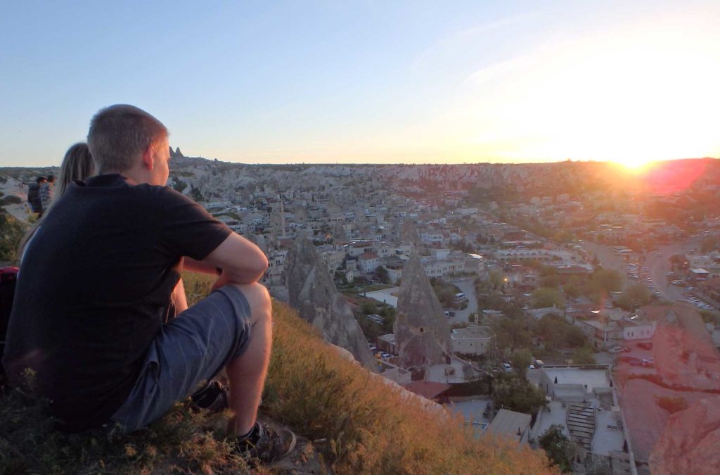 Casal assiste o pôr do sol nas colinas sobre a cidade de Goreme, na Turquia