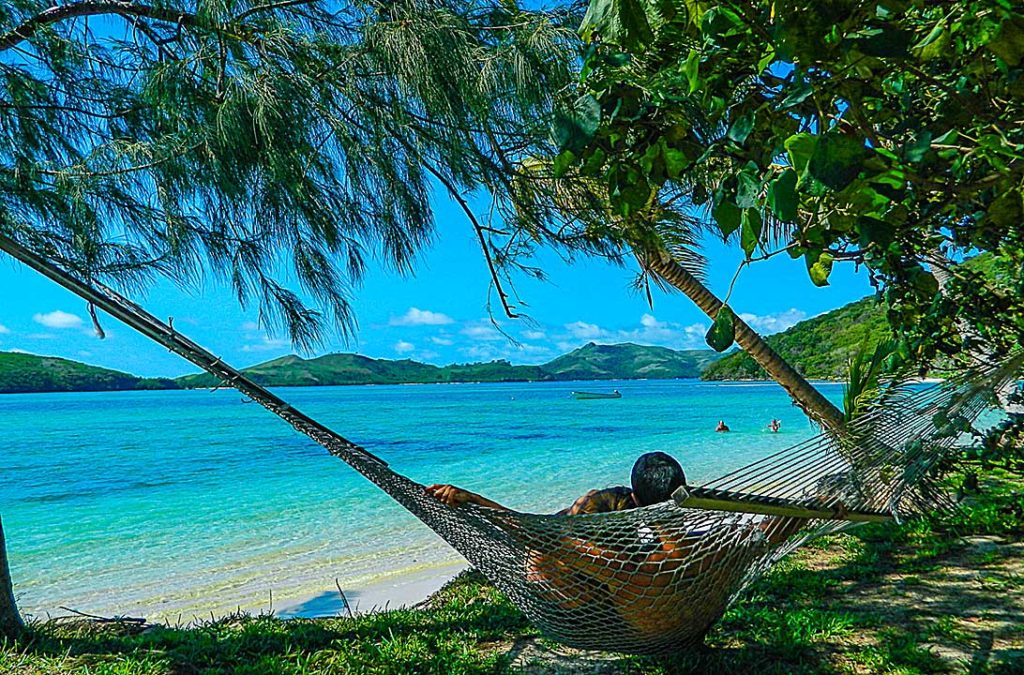 Casal deita abraçado em rede à beira do mar na Ilha de Matacavalewu, em Fiji