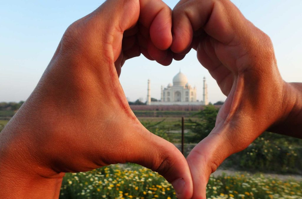 Pessoa faz coração com as mãos para enquadrar o Taj Mahal ao centro, em Agra (Índia)