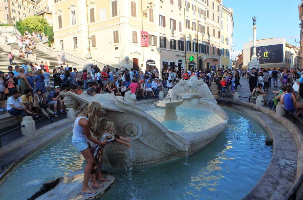 Mulher e menina se molham na água de fonte em Roma, na Itália