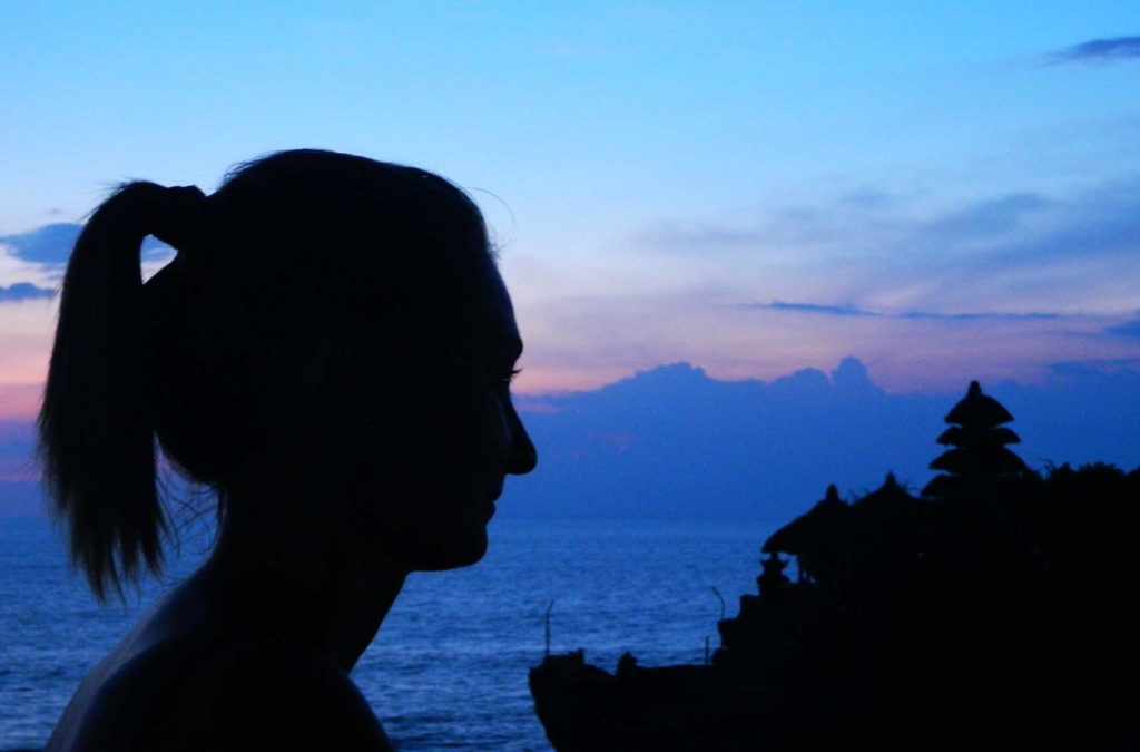 Silhueta de mulher e do templo de Tanah Lot ao anoitecer na Ilha de Bali