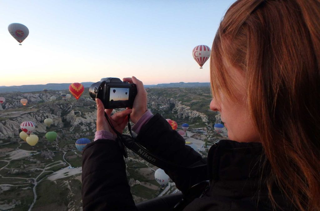 Mulher tira fotos dos balões voando nos céus da Capadócia (Turquia)