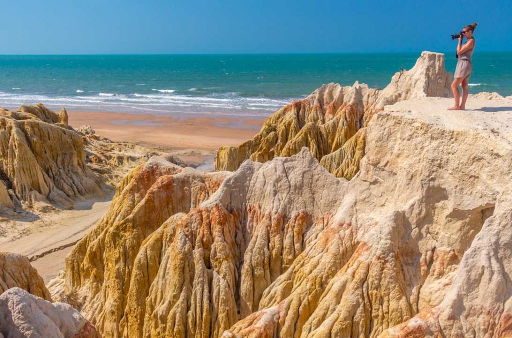 Mulher tira foto na Garganta do Diabo, em Canoa Quebrada (Ceará)