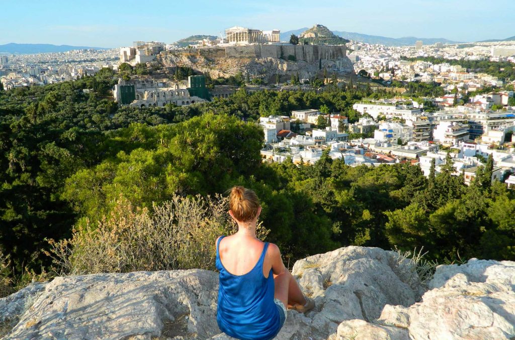 Mulher de costas admira a vista da Acrópole de Atenas desde a Colina Philopappos