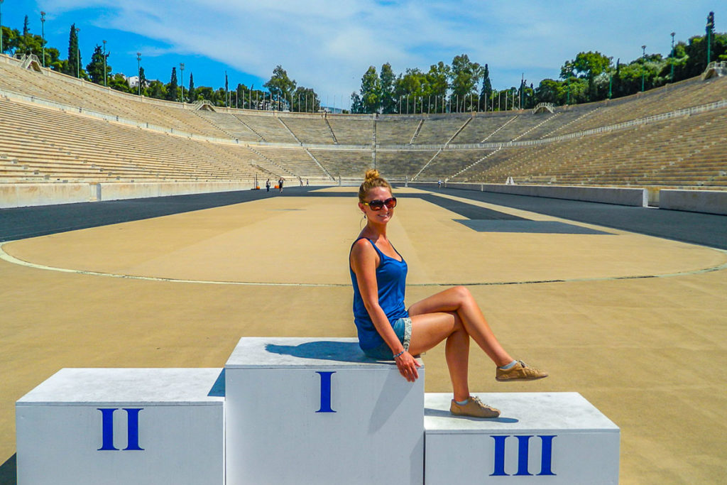 Mulher posa para foto no pódio do Estádio Panathinaikos, em Atenas