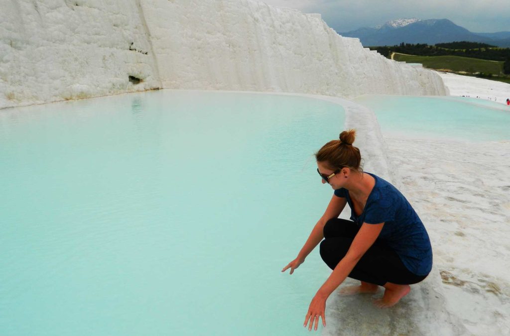 Mulher molha as mãos nos terraços de Pamukkale (Turquia)