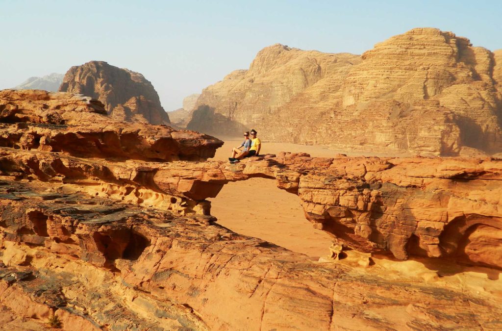 Casal posa na formação rochosa 'Rock Bridge', no Deserto de Wadi Rum (Jordânia)