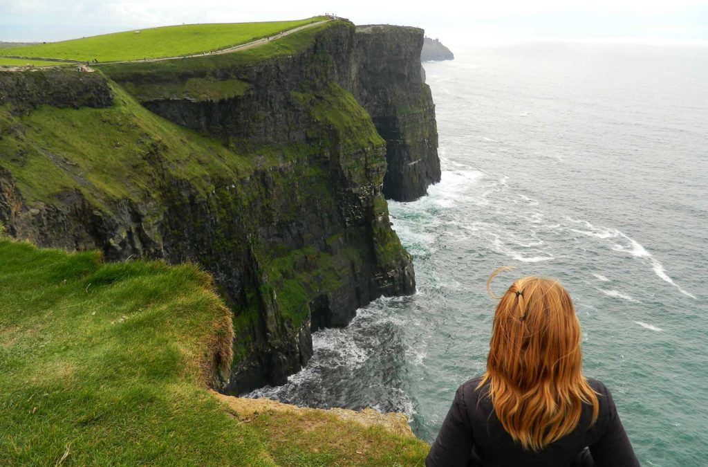 Mulher admira os Cliffs of Moher (Irlanda)