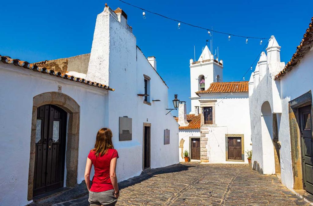 Mulher caminha pelas ruas de pedra do vilarejo de Monsaraz, em Portugal