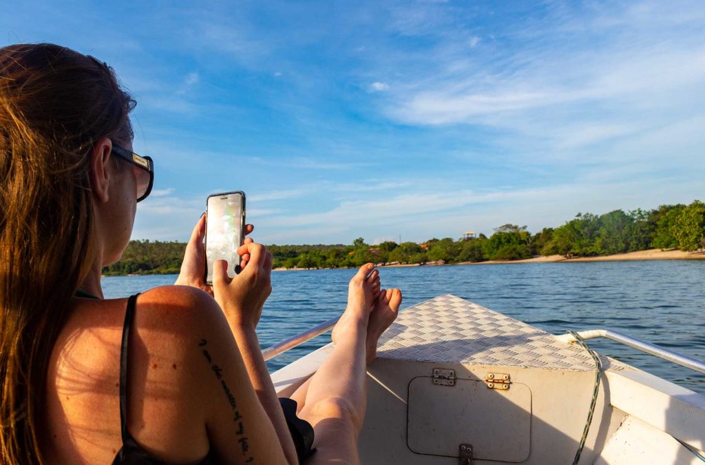 Mulher mexe no celular durante passeio de barco em Alter do Chão, no Pará (Brasil)