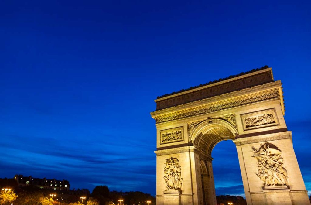 Arco do Triunfo iluminado ao anoitecer, em Paris