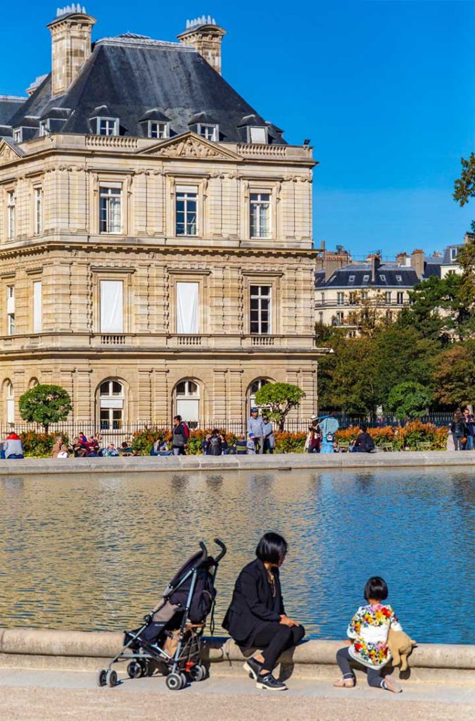 Mulher e criança na beira do lago em frente ao palácio do Jardim de Luxemburgo, em Paris