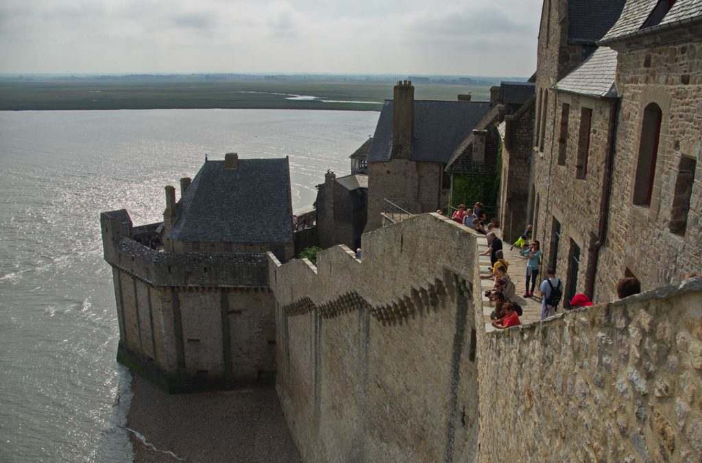 Visitantes observam a maré alta cercar o Mont Saint-Michel, na França