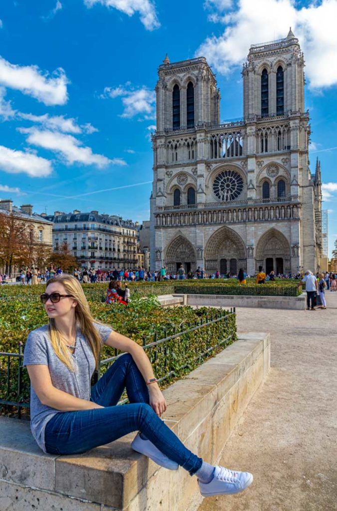 Mulher posa para foto na praça em frente à Catedral de Notre-Dame, em Paris