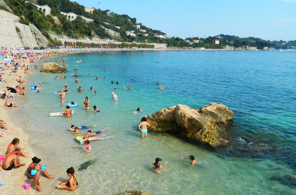 Pessoas tomam banho de mar na praia de Villefranche-sur-Mer, na França