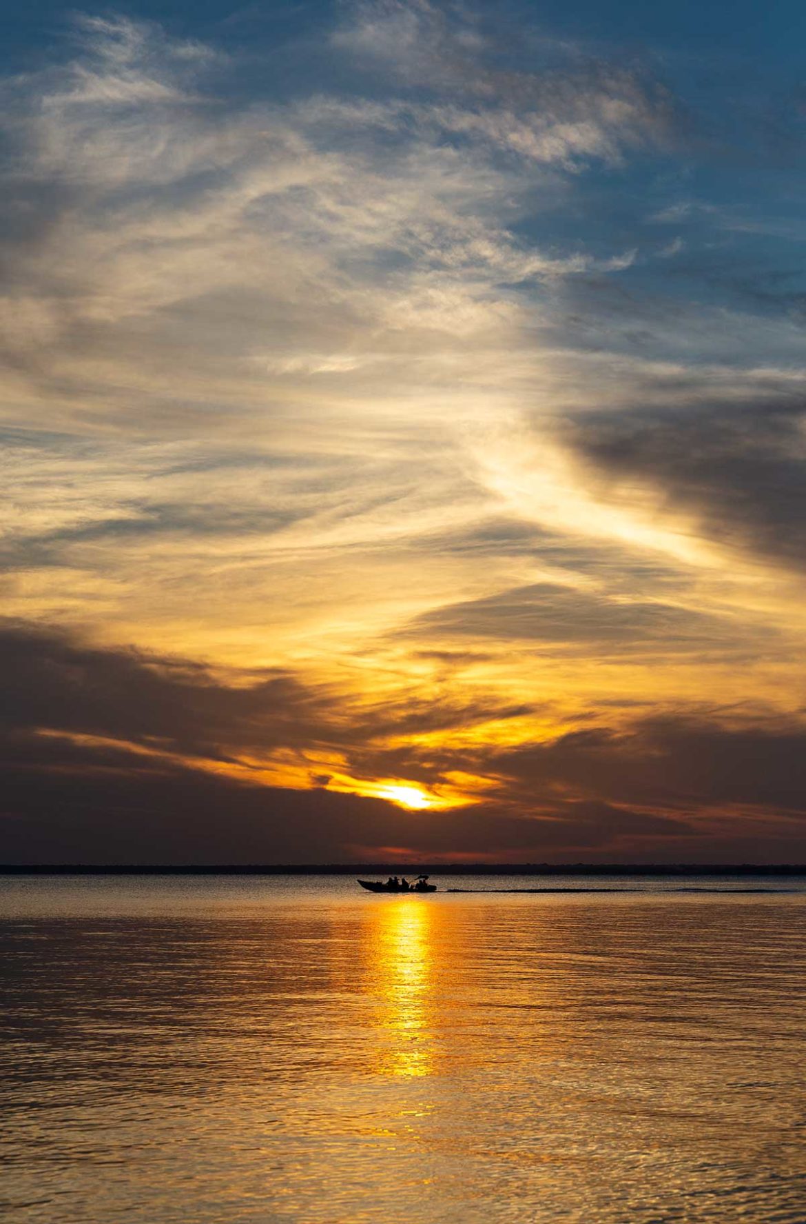Barco passa no Rio Tapajós ao pôr do sol em Alter do Chão, no Pará (Brasil)