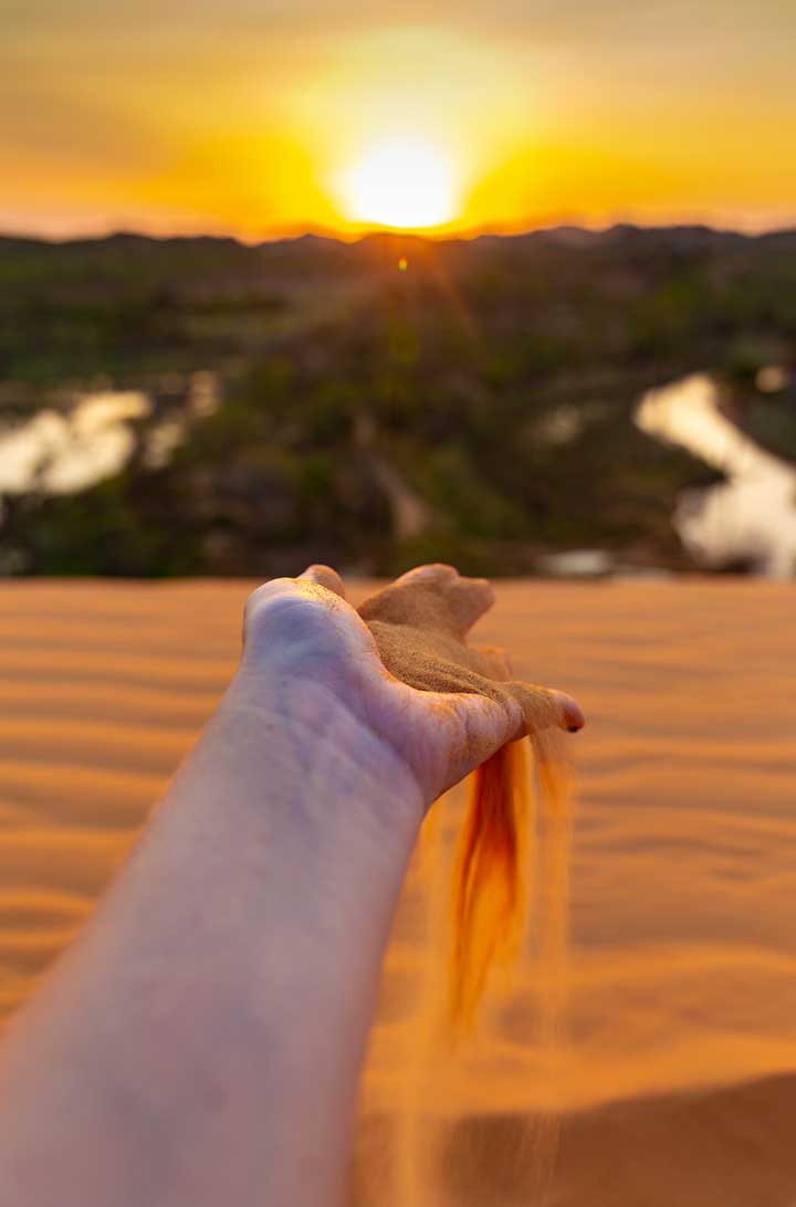 Areia escorre pelos dedos de visitante durante o pôr do sol nas dunas do Jalapão, no Tocantins (Brasil)
