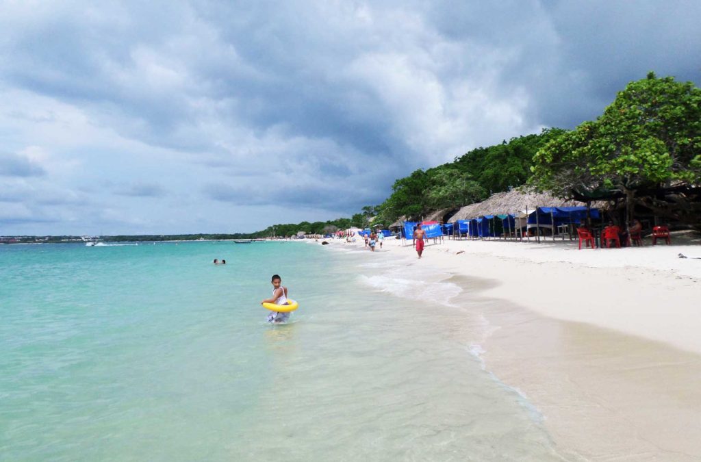 Menino entra de boia no mar na Playa Blanca, em Cartagena (Colômbia)