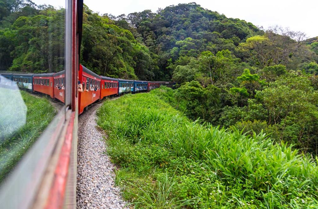 Turistas tiram fotos pelas janelas do trem Curitiba-Morretes, no Paraná (Brasil)