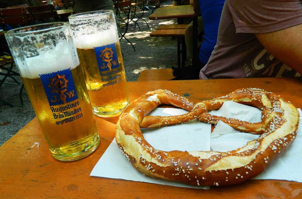 Canecas de chope e pretzel sobre uma das mesas do 'biergarten' Augustiner-Keller, em Munique