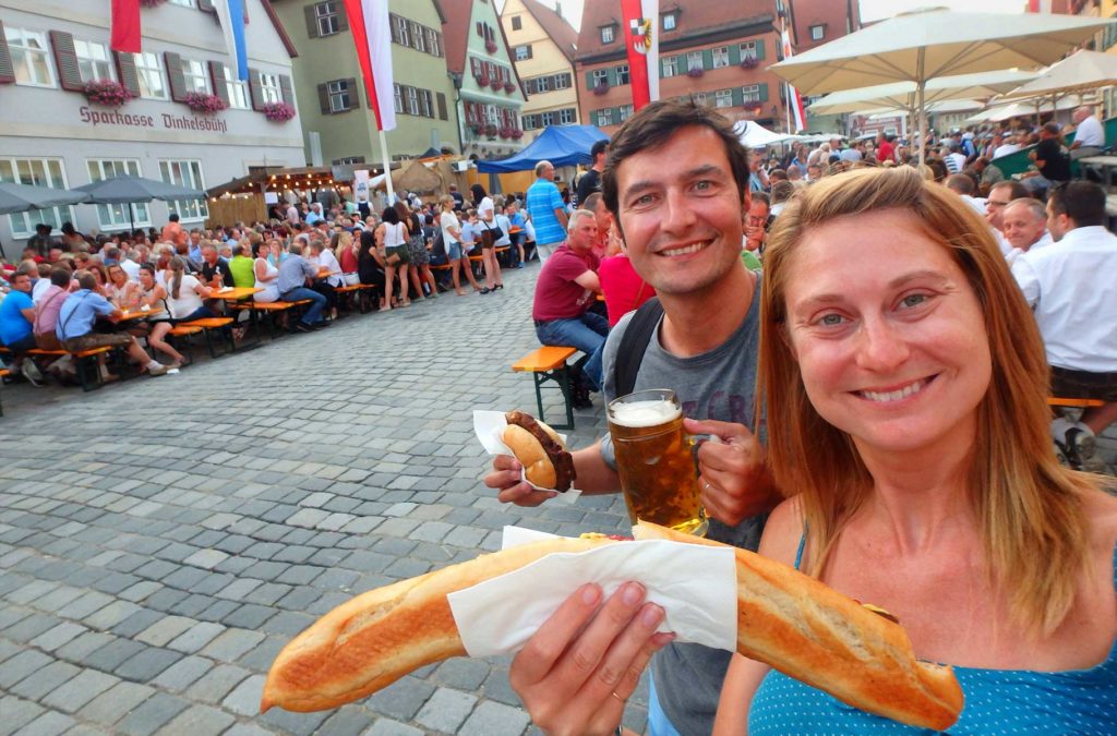 Casal de turistas come comida típica alemã durante festa em Dinkelsbühl