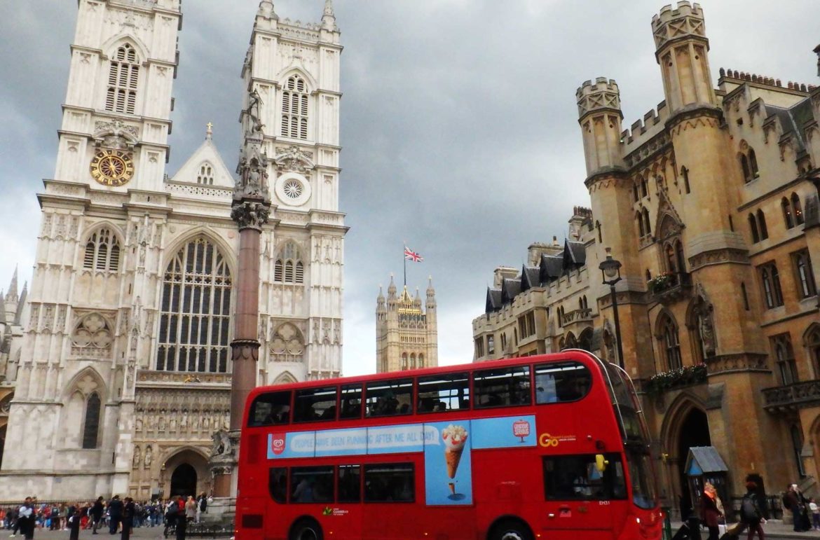 Ônibus vermelho de dois andares, típico de Londres, passa em frente à Abadia de Westminster