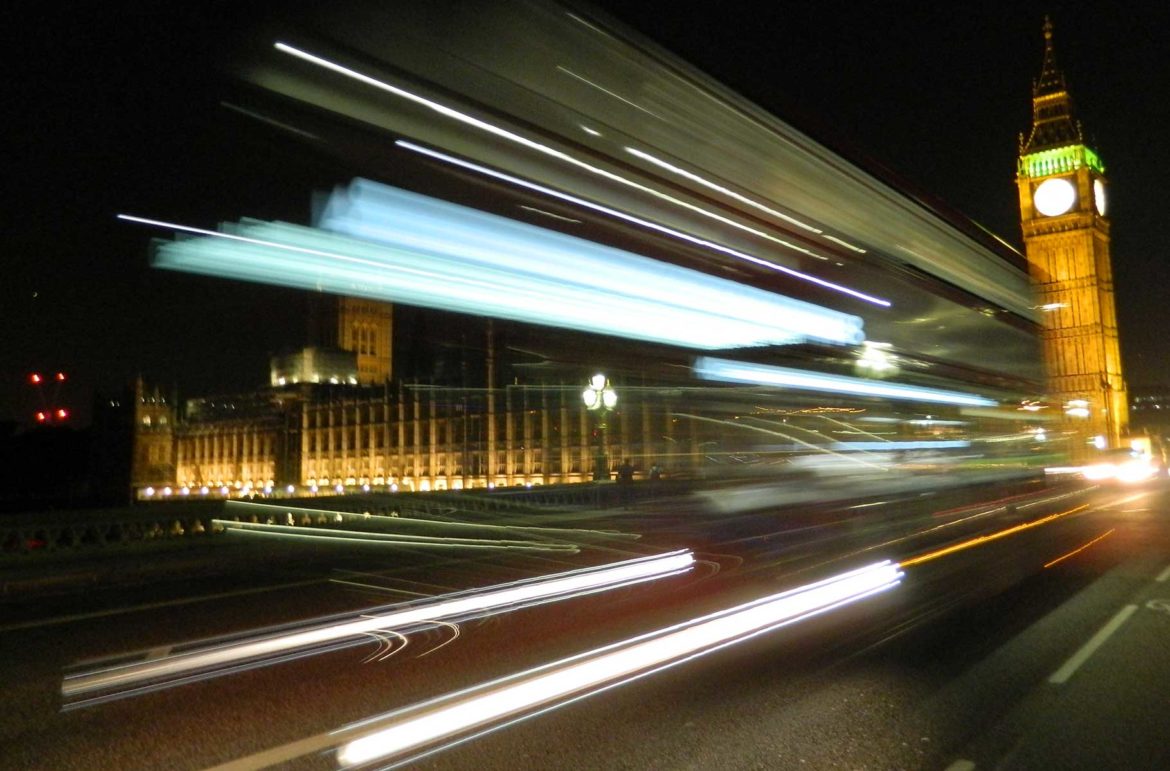Tradicional ônibus de dois andares passa em frente ao Parlamento britânico, com iluminação noturna