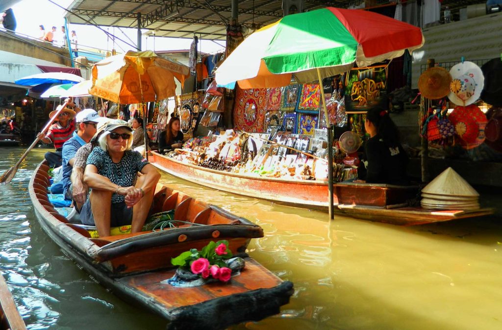 Turistas passeiam de barco entre os vendedores do Mercado Flutuante de Damnoen Saduak