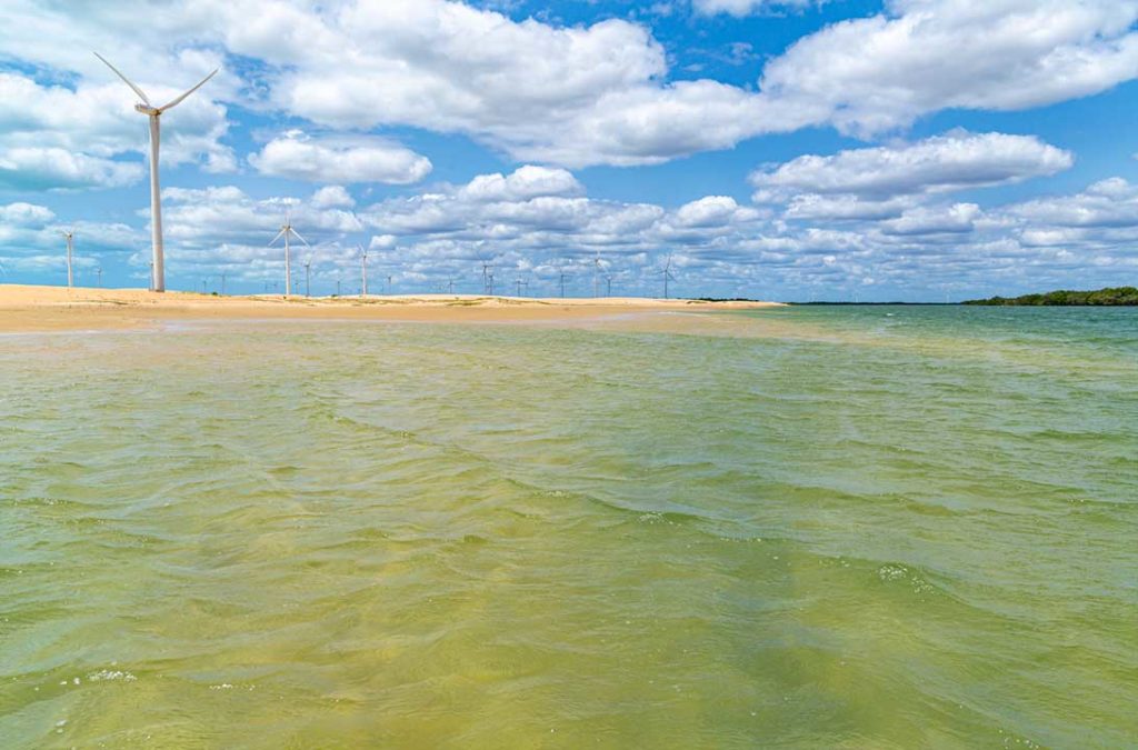 A praia da Duna do Capim, com os geradores de energia eólicos ao fundo