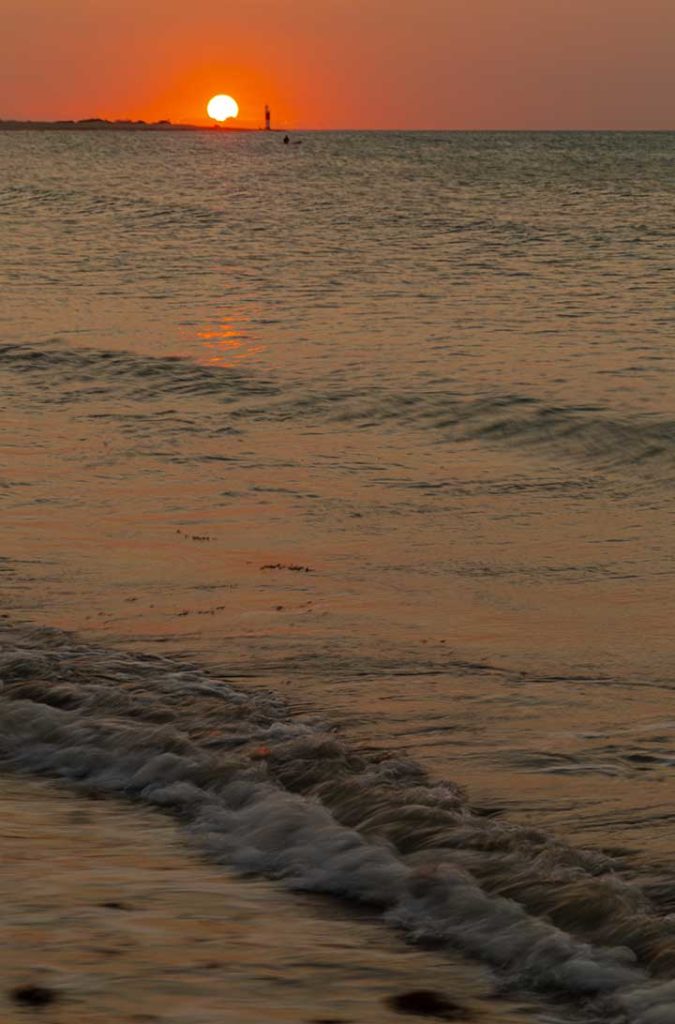 Pôr do sol ao lado do farol visto da praia principal de Galinhos