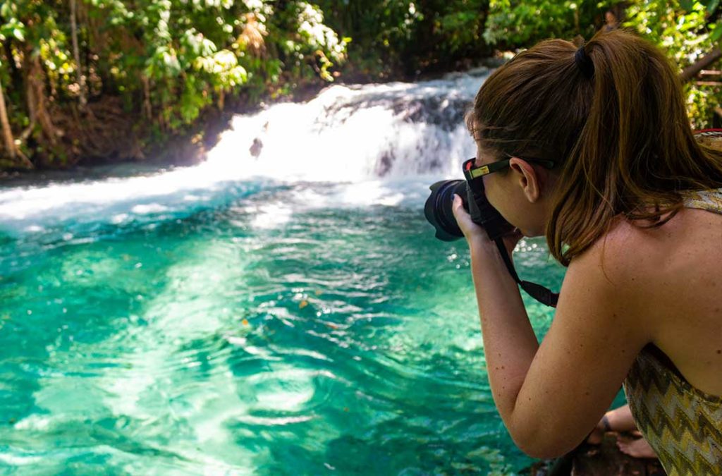 Turista fotografa as águas muito azuis da Cachoeira do Formiga